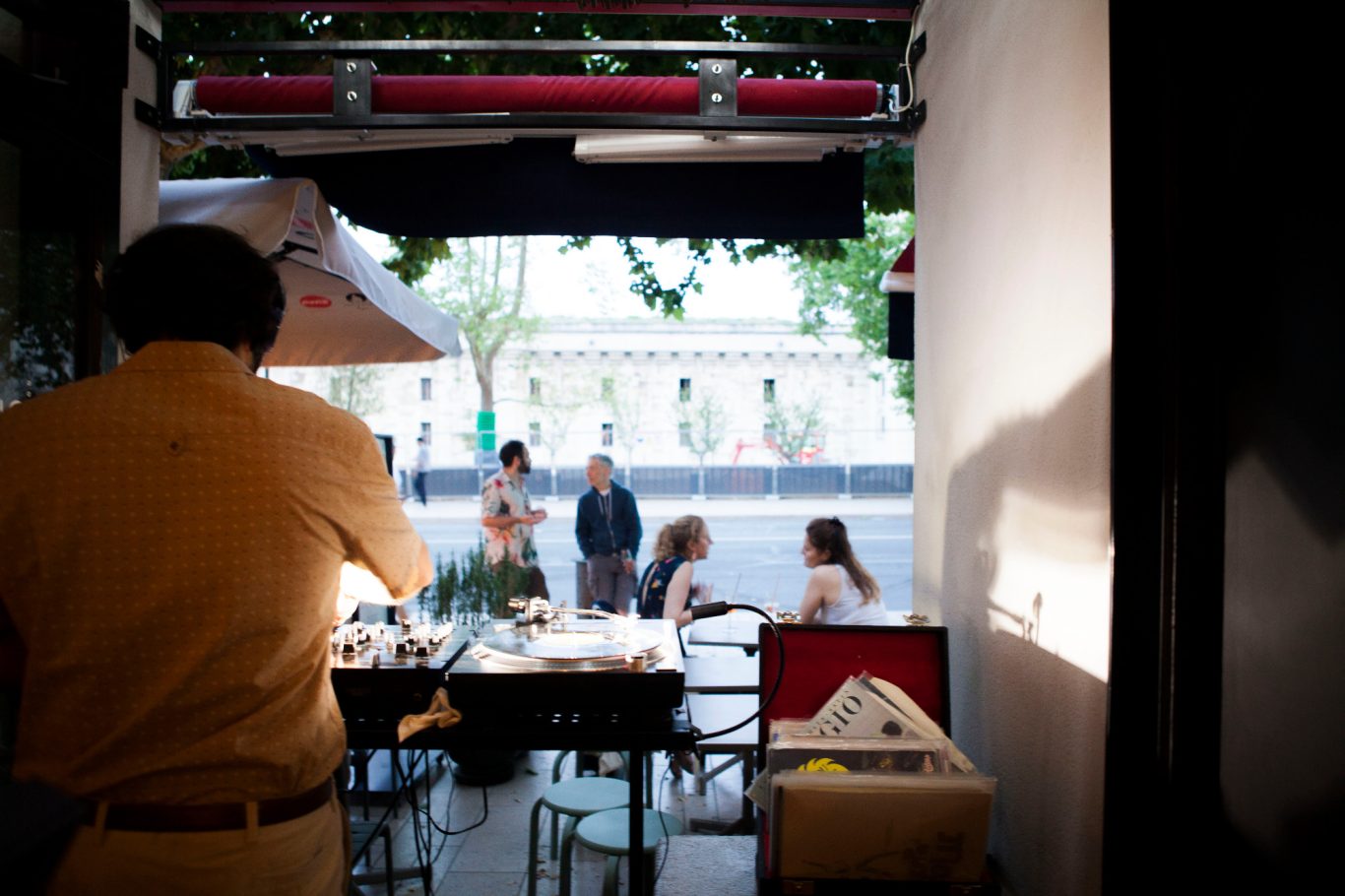 Serveur en train de préparer une table à l'extérieur d'un café animé.