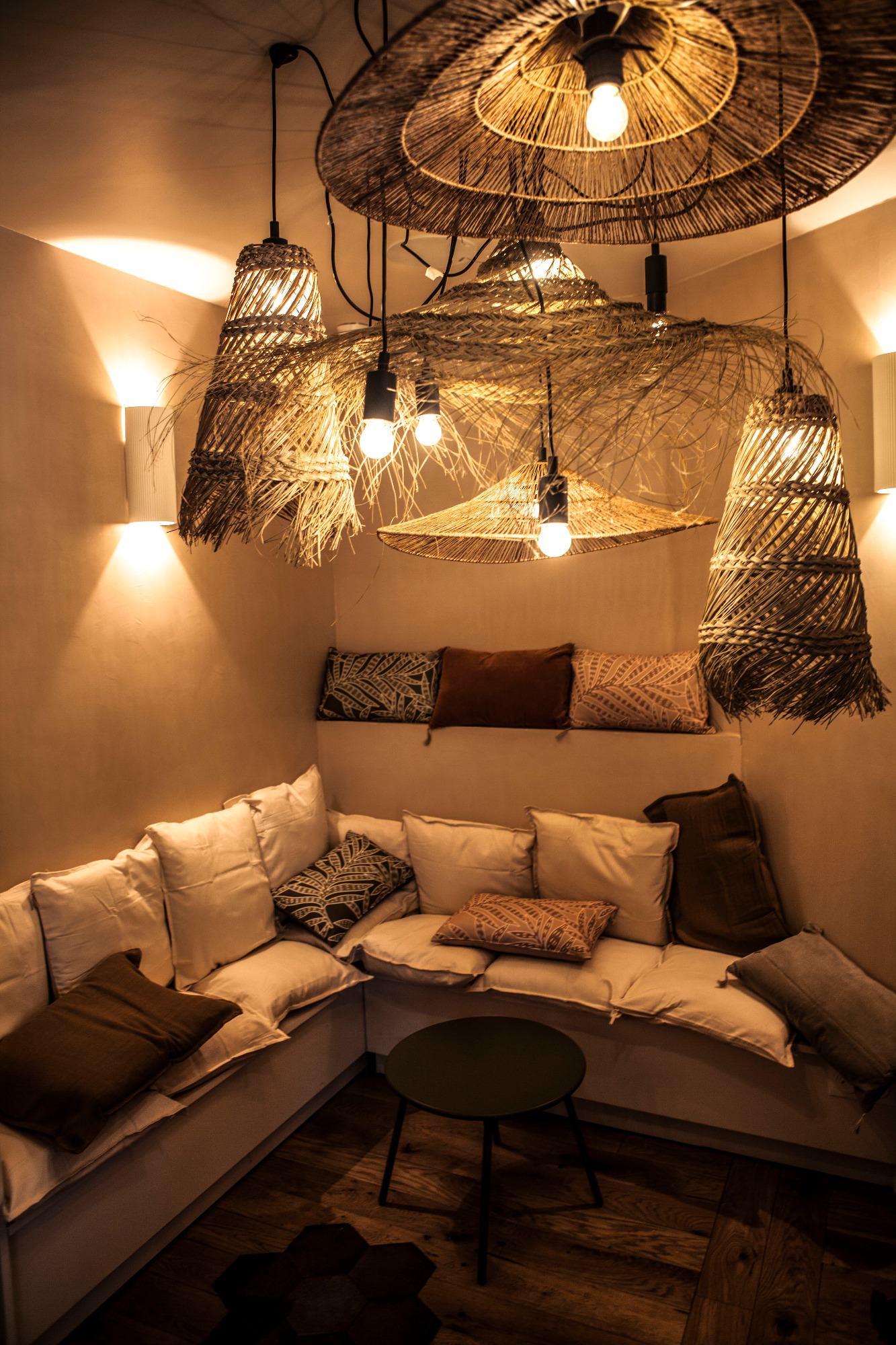 Coin salon confortable avec coussins, éclairage tamisé et décor en macramé.